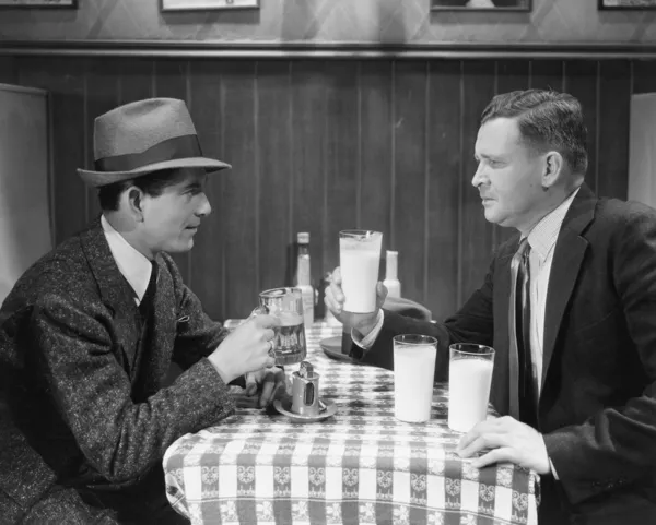 Deux hommes à une table entrain de boire des verres de bière